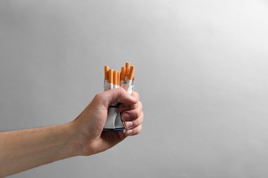 Photo of Stop smoking. Man holding pack with cigarettes on grey background, closeup. Space for text