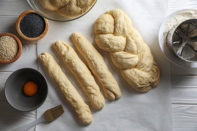 Homemade braided bread and ingredients on white wooden table, flat lay. Cooking traditional Shabbat challah
