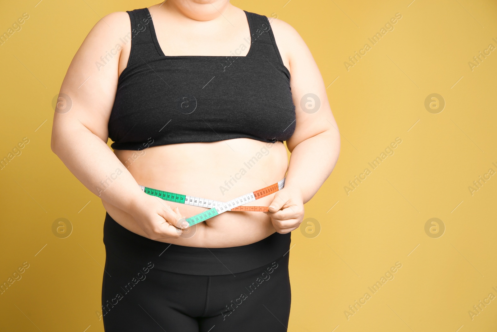 Photo of Overweight woman with measuring tape on color background