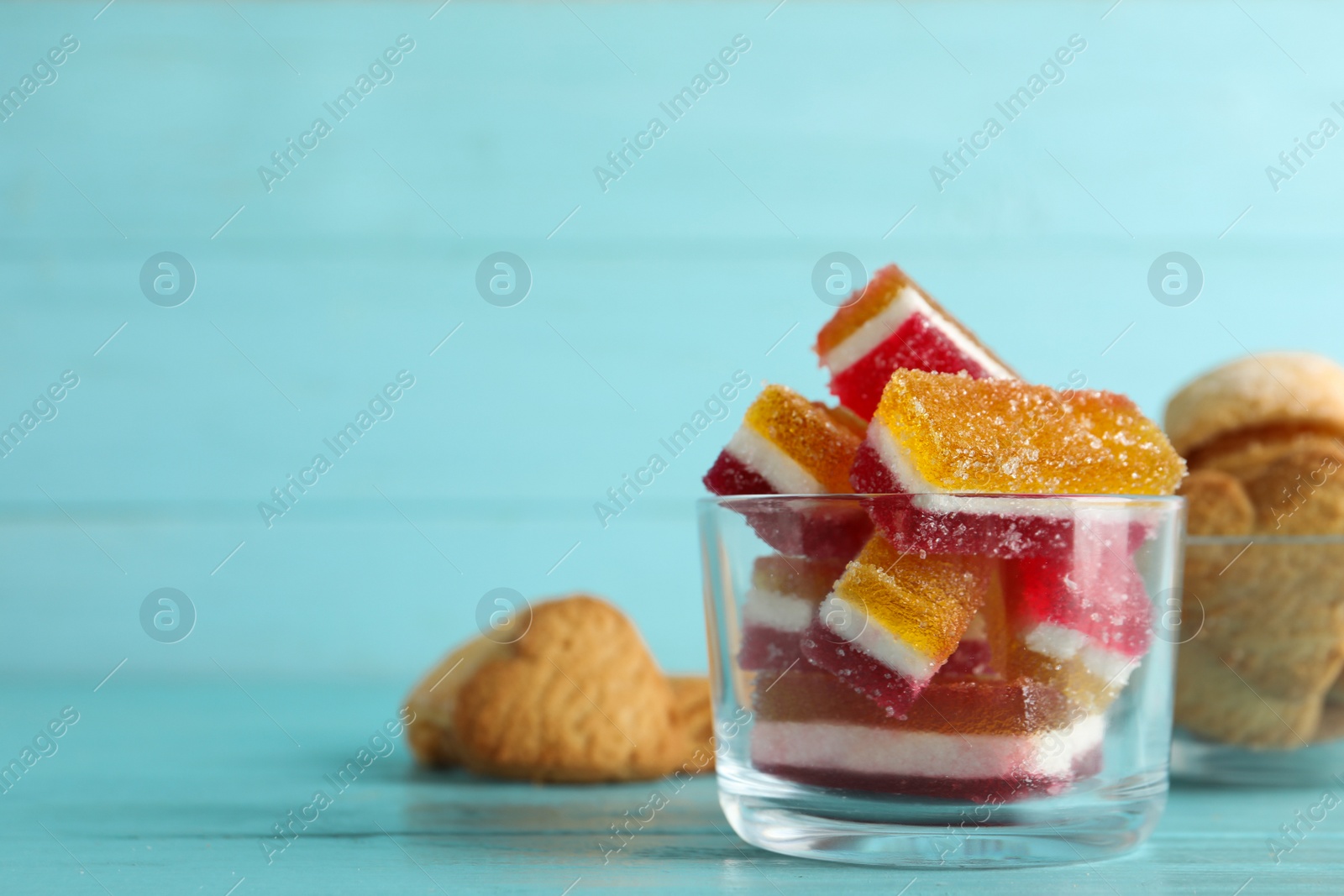 Photo of Bowl with delicious colorful jelly candies on light blue wooden table, closeup. Space for text