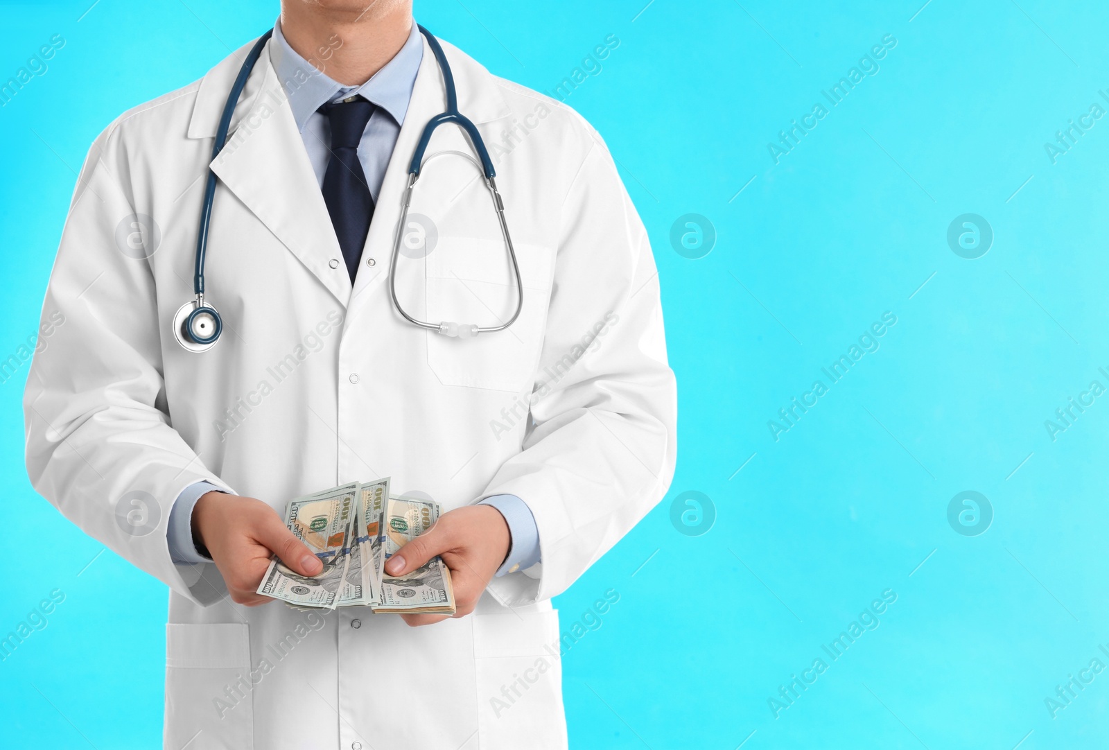 Photo of Doctor with bribe on light blue background, closeup. Corruption in medicine