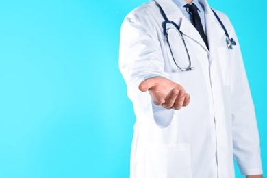 Photo of Male doctor offering helping hand on color background, closeup with space for text