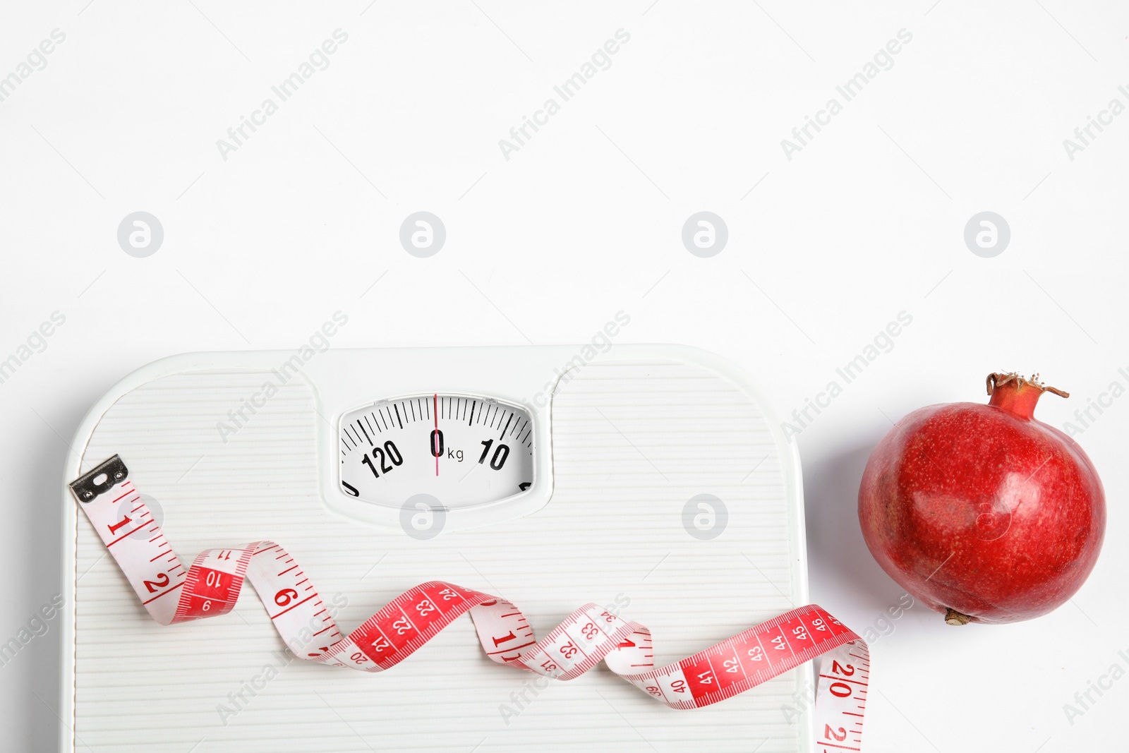 Photo of Composition with scales, tape measure and pomegranate on white background, top view