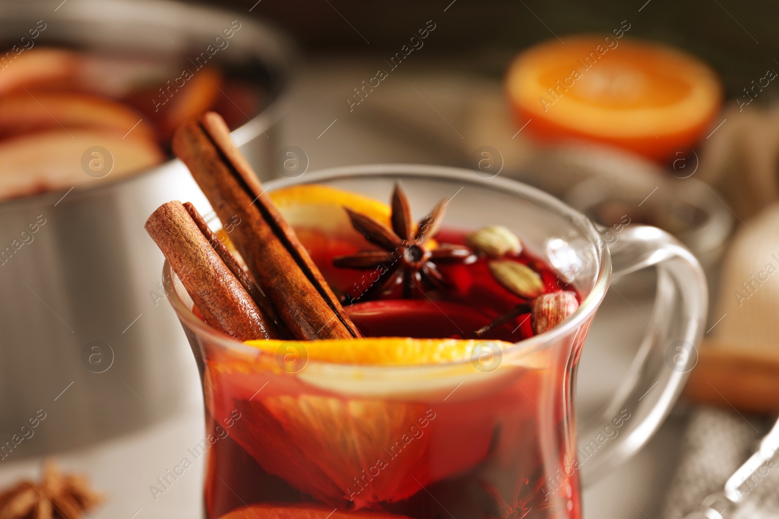 Photo of Glass cup of tasty mulled wine with spices, closeup