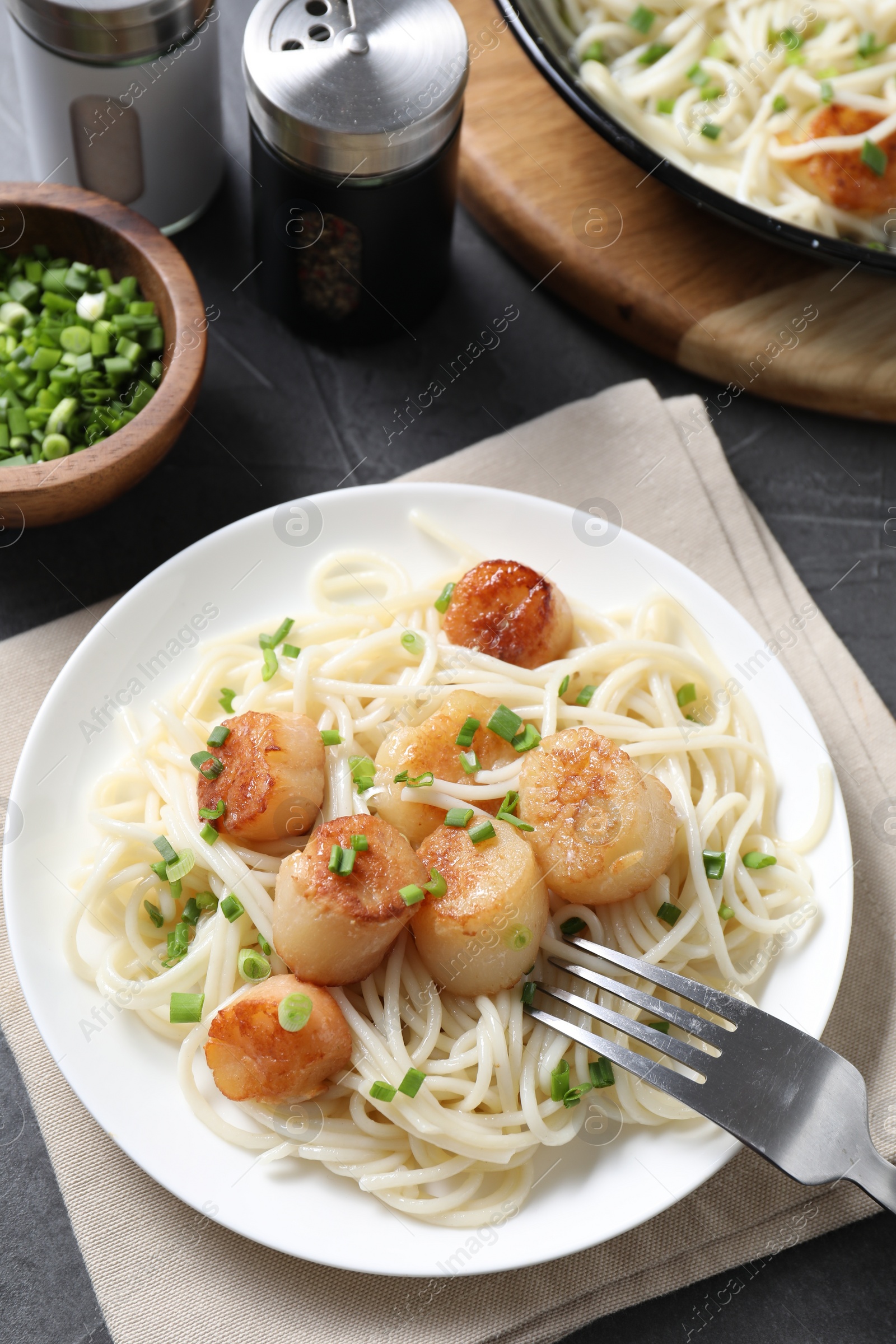 Photo of Delicious scallop pasta with green onion served on grey table, flat lay