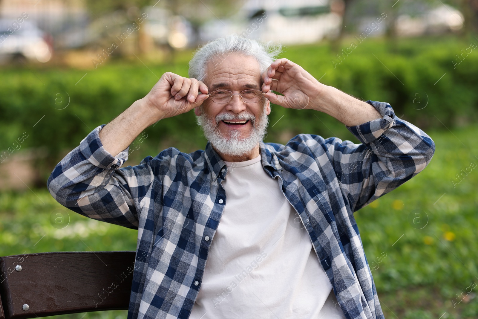 Photo of Portrait of happy grandpa with glasses on bench in park