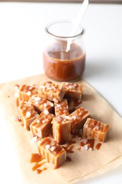 Photo of Tasty candies, caramel sauce and salt on white table