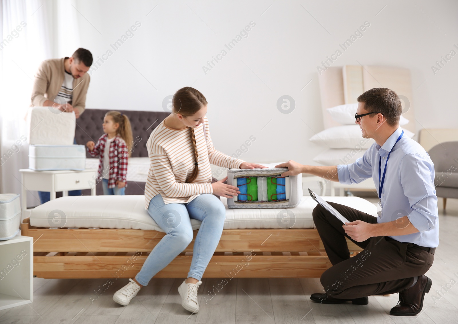 Photo of Salesman showing young woman section of mattress in store