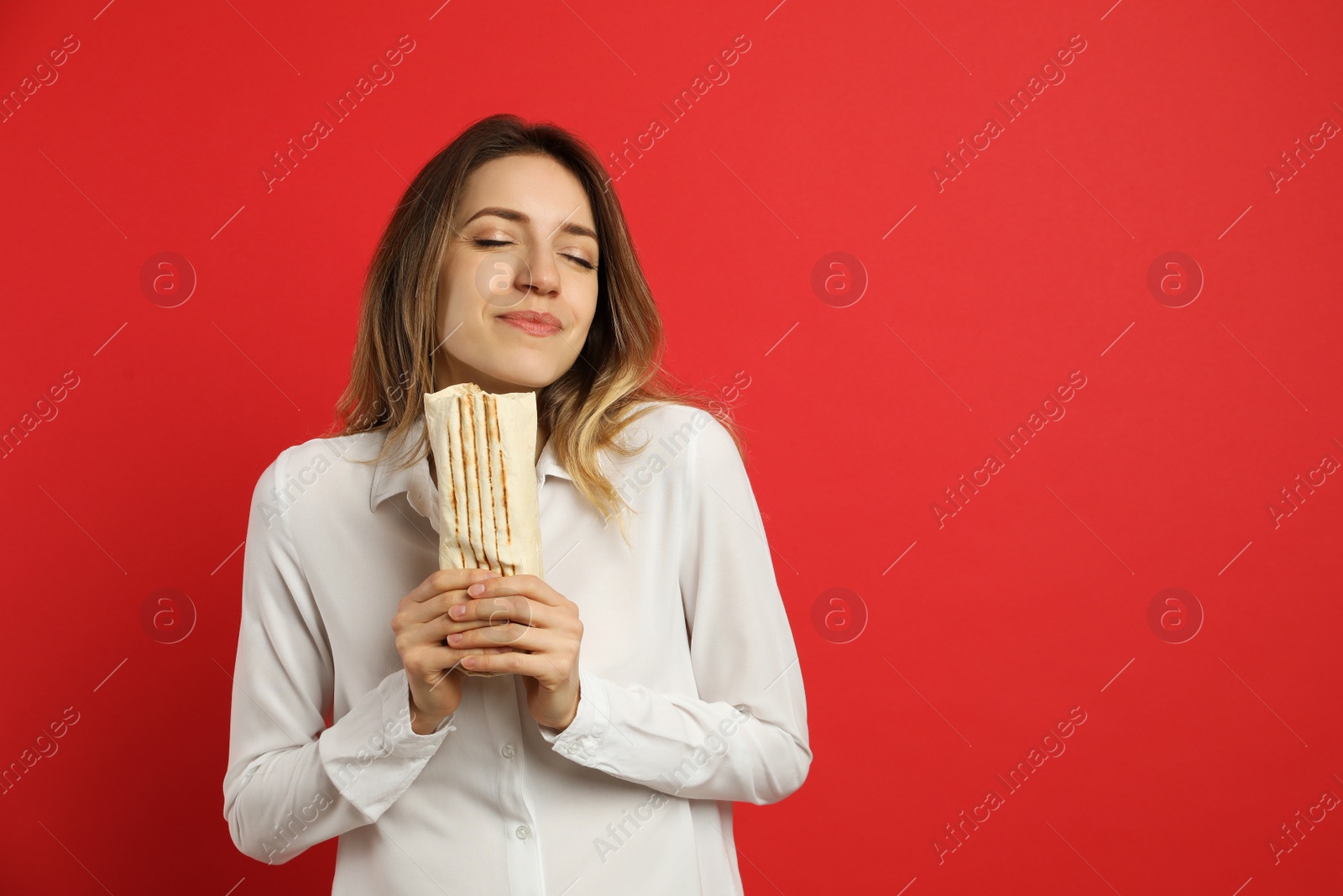 Photo of Young woman with delicious shawarma on red background, space for text