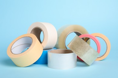 Photo of Many rolls of adhesive tape on light blue background