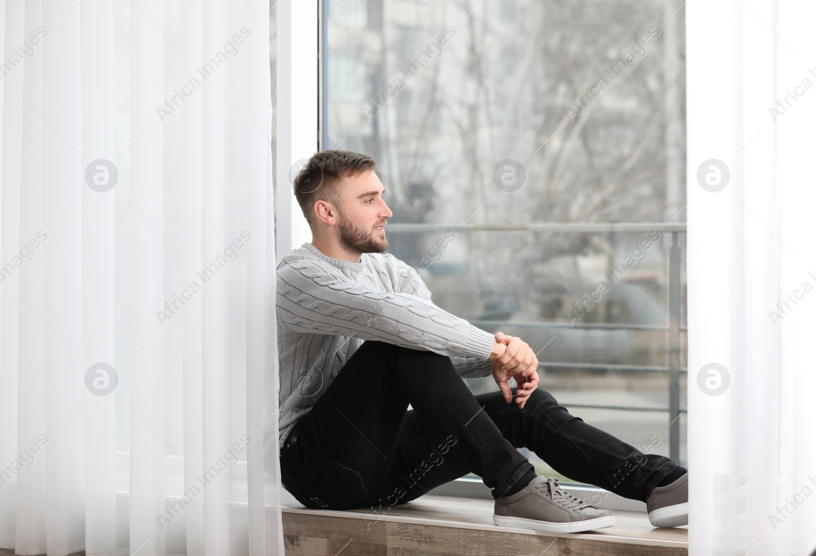 Photo of Handsome young man near window at home