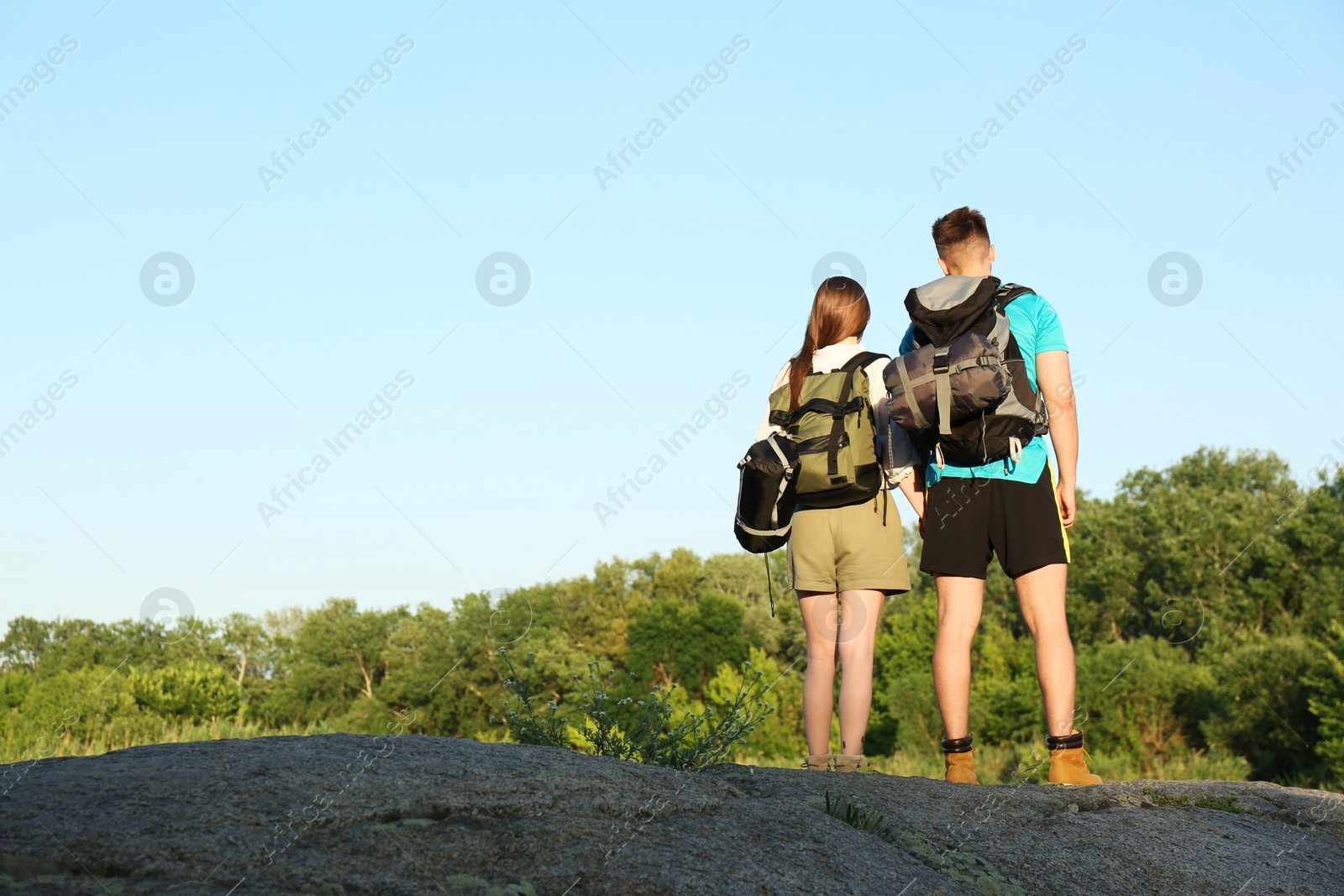 Photo of Young couple with sleeping bags outdoors. Space for text