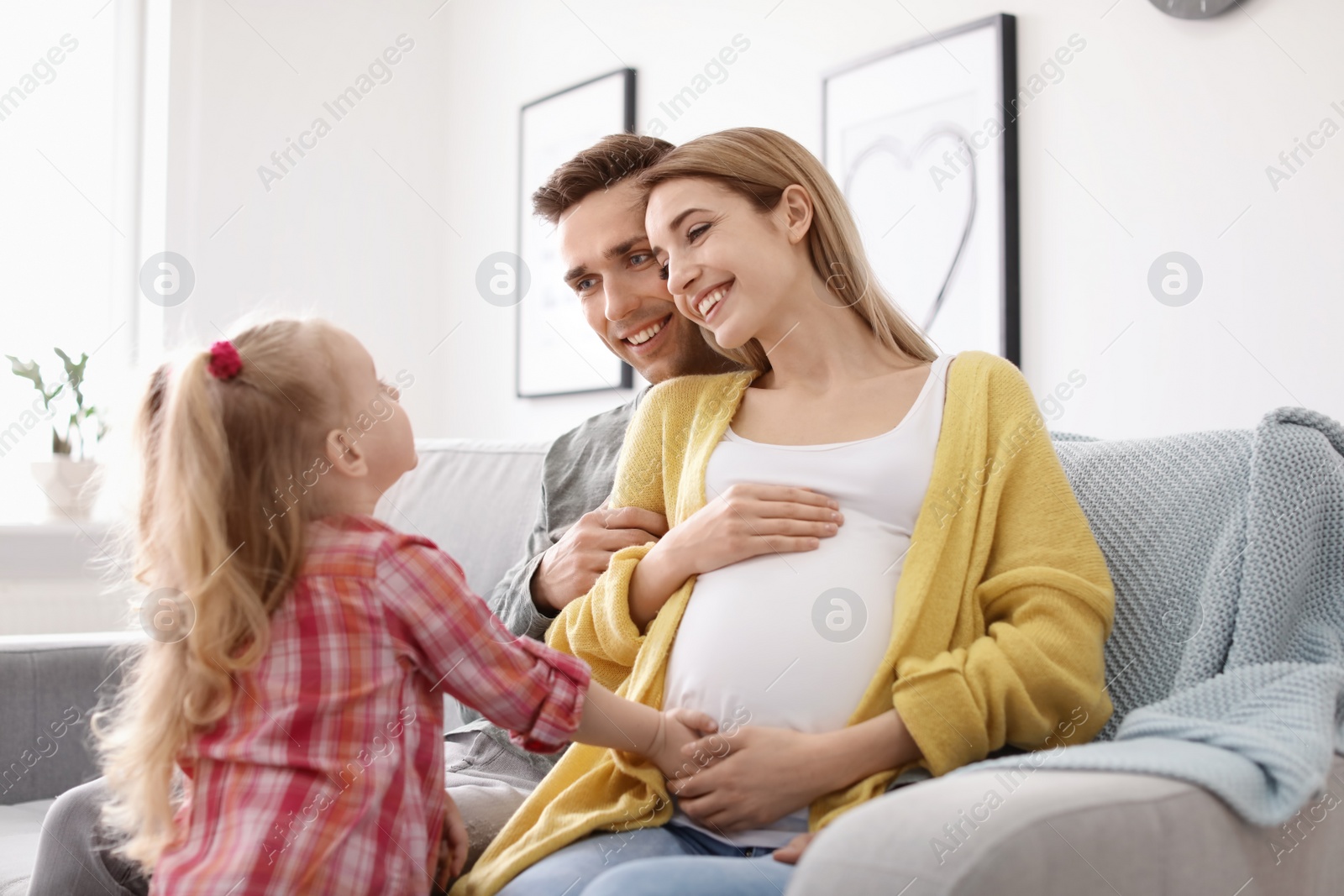 Photo of Young pregnant woman with her family at home