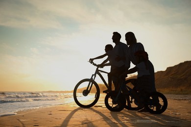 Silhouette of family on seashore at sunset