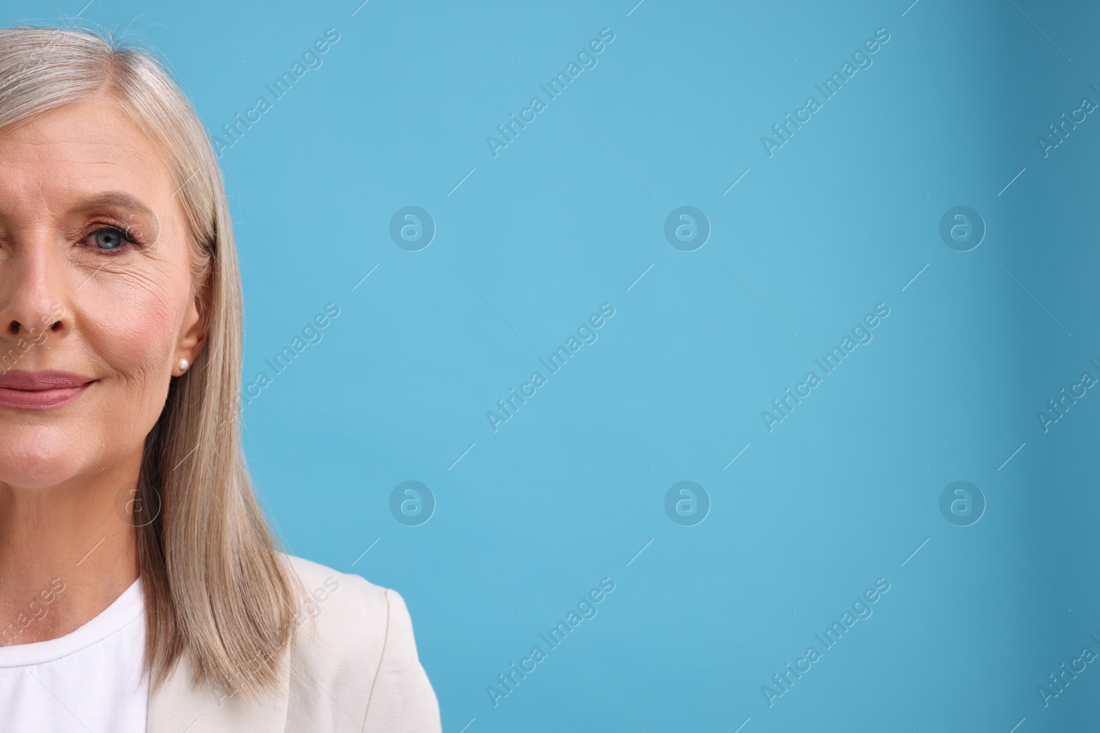 Photo of Portrait of beautiful middle aged woman on light blue background, closeup. Space for text