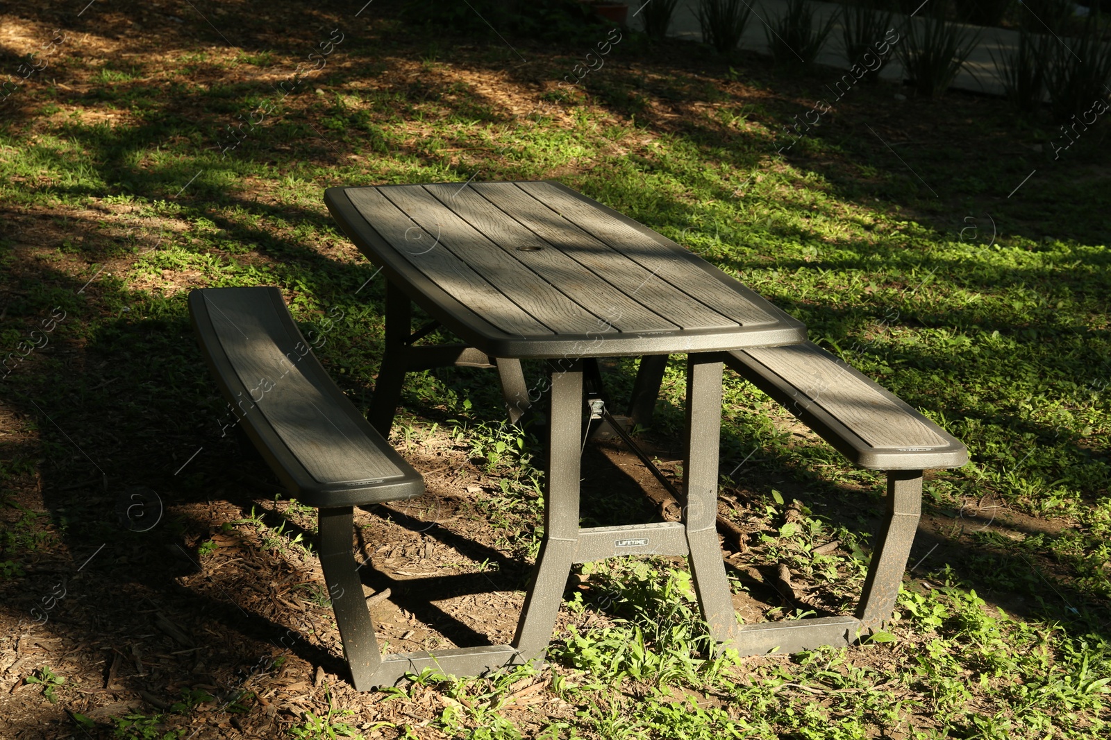 Photo of Empty wooden picnic table with benches in park on sunny day