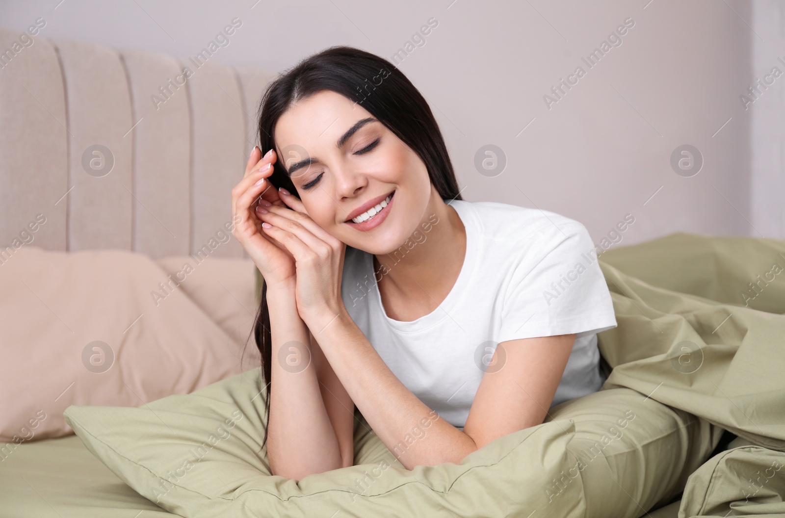 Photo of Woman lying in comfortable bed with green linens