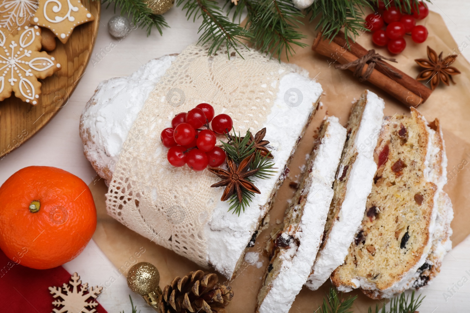 Photo of Traditional Christmas Stollen with icing sugar on white table, flat lay
