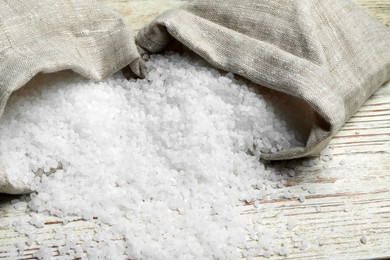 Photo of Bags with natural sea salt on white wooden table, closeup