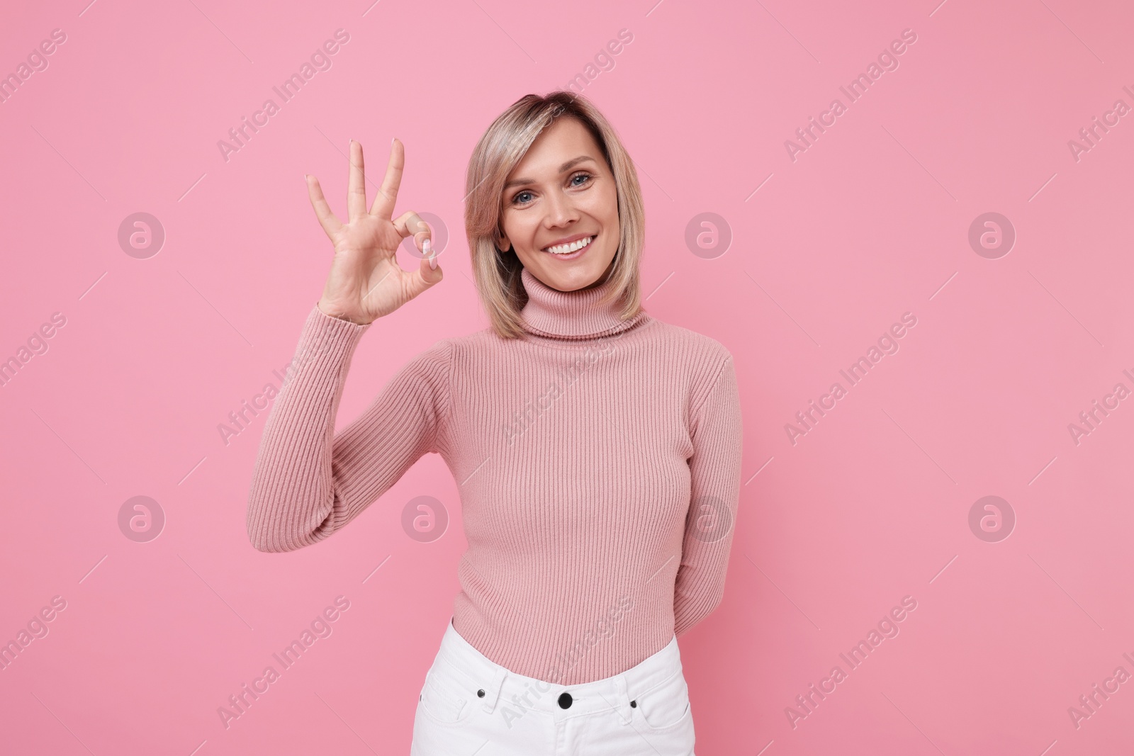 Photo of Happy woman showing ok gesture on pink background