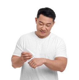 Handsome man applying body cream onto hand on white background