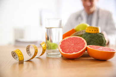 Healthy products, measuring tape and blurred nutritionist on background