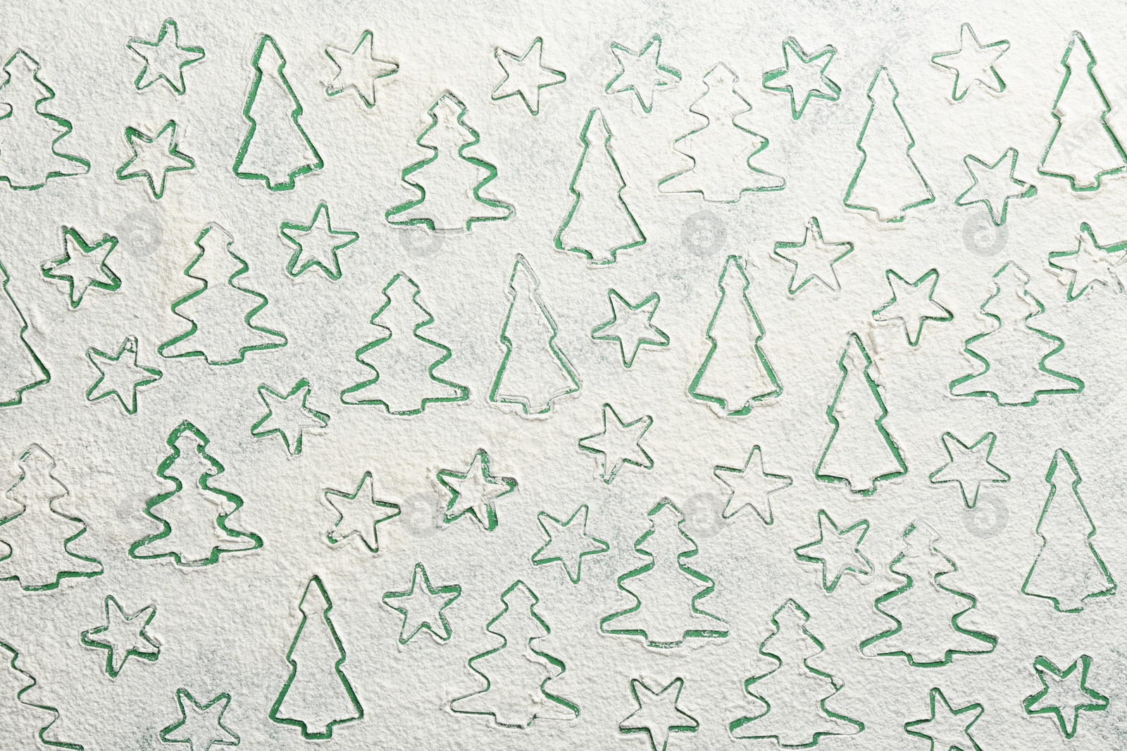 Photo of Different Christmas cookie shapes made of flour on green background, top view