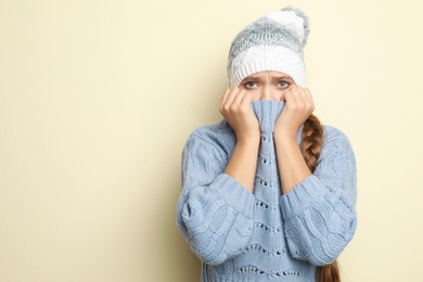 Young woman wearing hat suffering from fever on light background, space for text. Cold symptoms