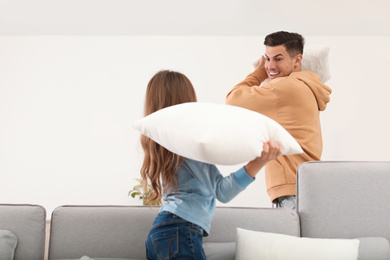 Photo of Happy father and daughter having pillow fight in living room