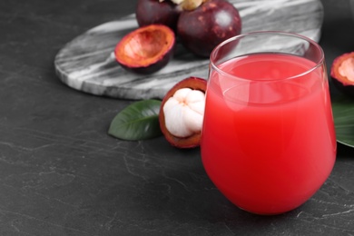 Photo of Delicious fresh mangosteen juice on dark table. Space for text