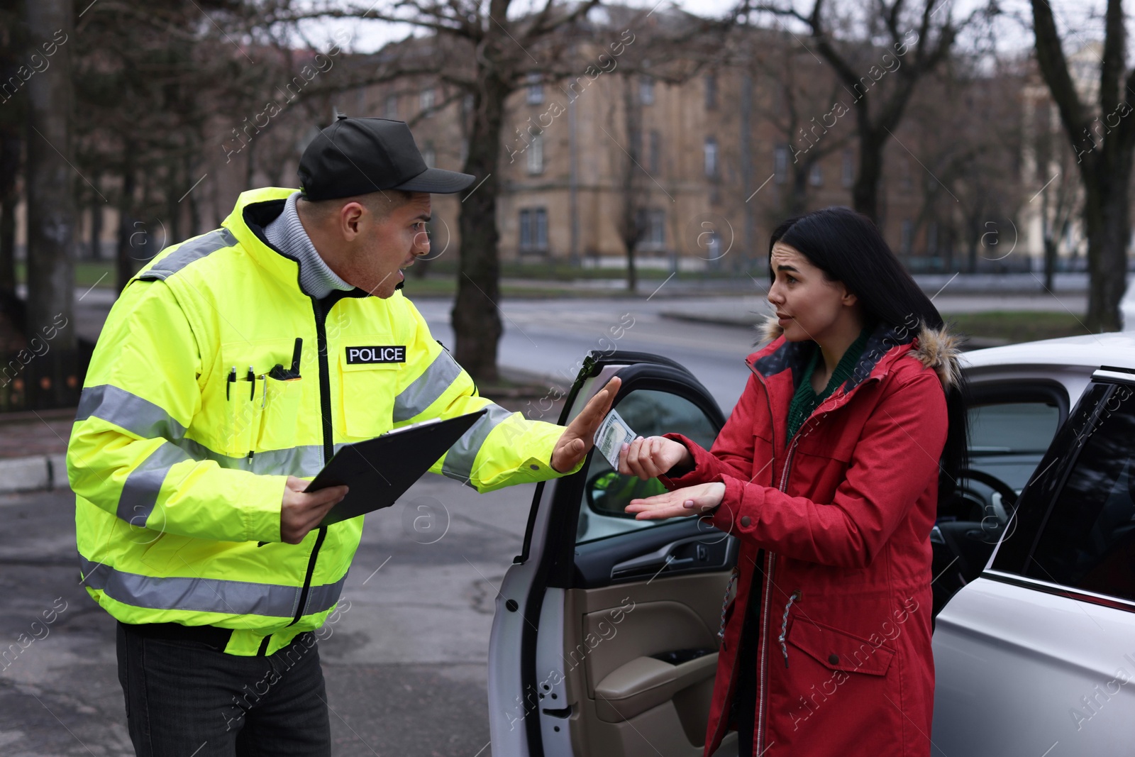 Photo of Police officer rejecting bribe near car outdoors