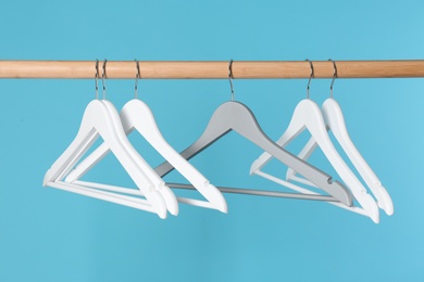 Photo of Wooden rack with clothes hangers on color background