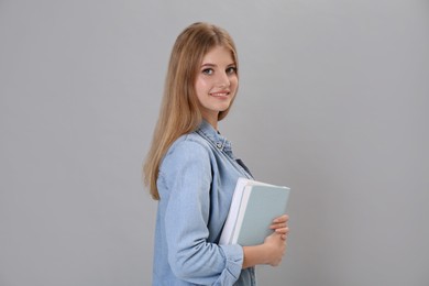 Photo of Teenage student holding books on grey background