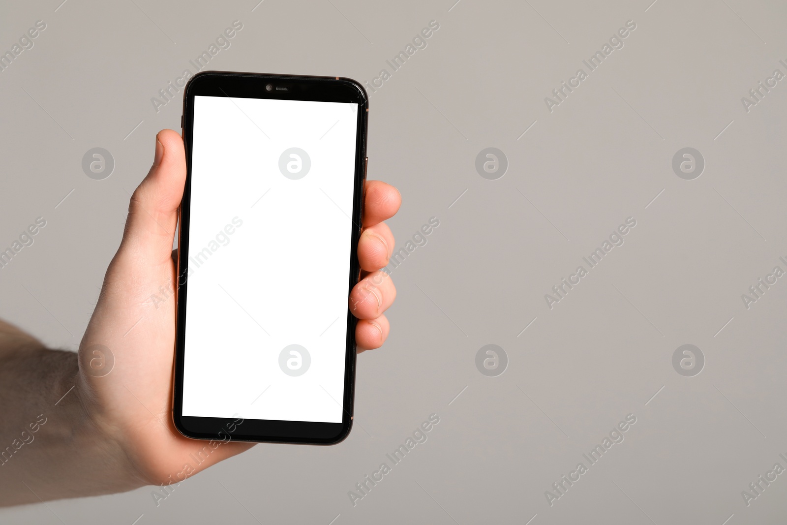 Photo of Man holding smartphone with blank screen on light grey background, closeup. Mockup for design