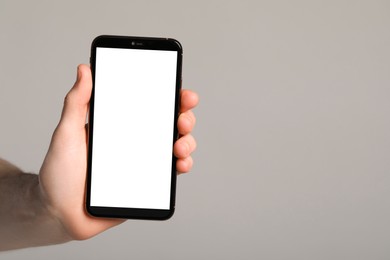 Photo of Man holding smartphone with blank screen on light grey background, closeup. Mockup for design