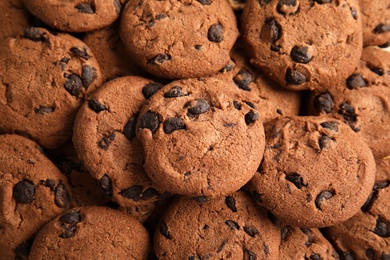 Tasty chocolate chip cookies as background, top view