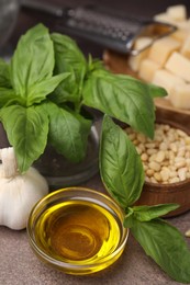 Photo of Different ingredients for cooking tasty pesto sauce on brown textured table, closeup