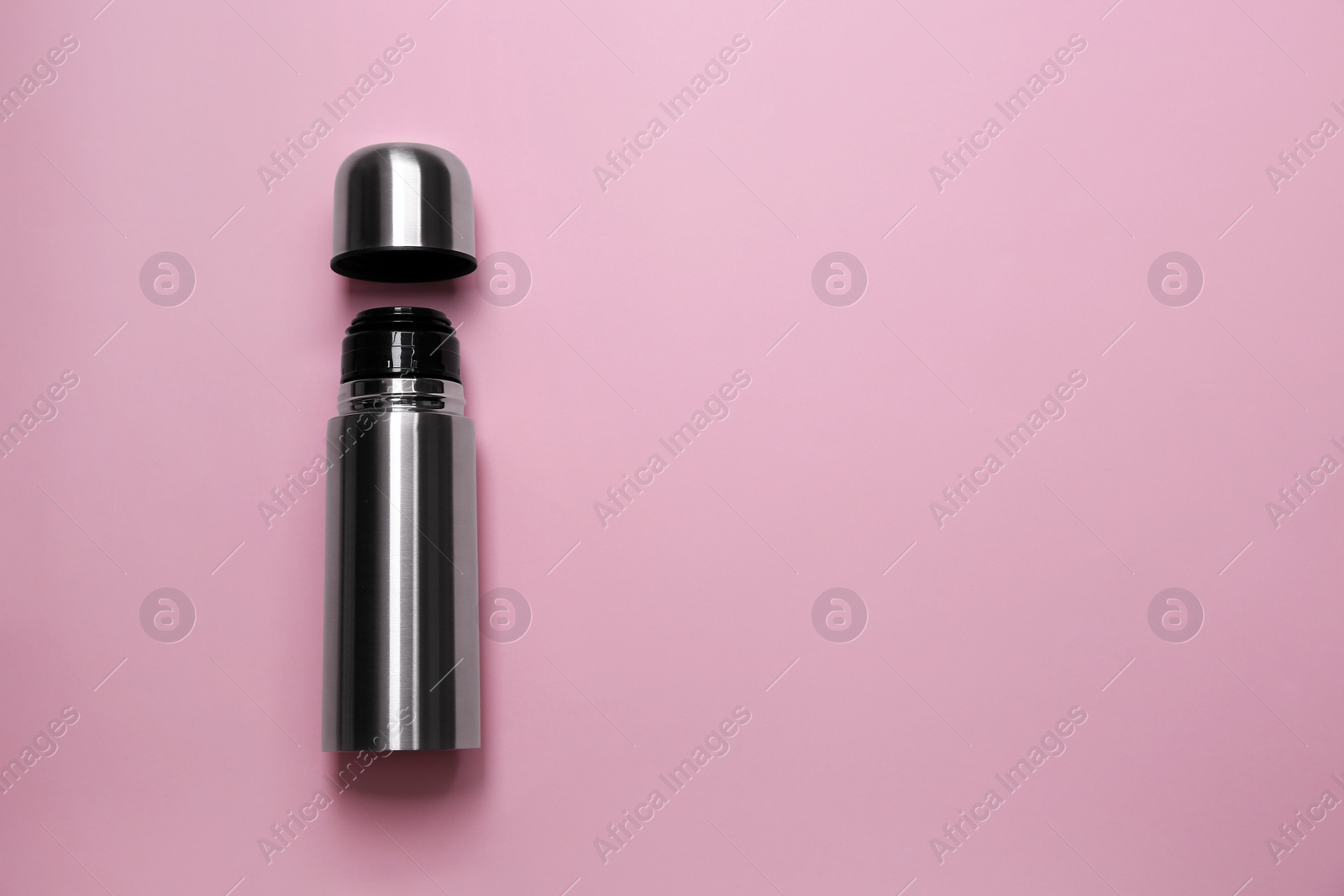 Photo of Stainless steel thermos on pink background, top view. Space for text