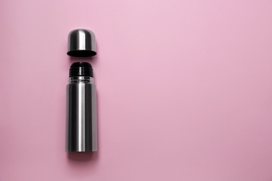 Photo of Stainless steel thermos on pink background, top view. Space for text