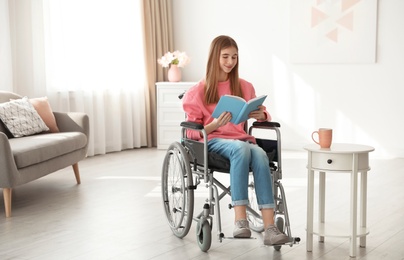 Photo of Teenage girl with book in wheelchair at home