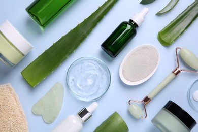 Flat lay composition with cosmetic products and cut aloe leaves on light blue background