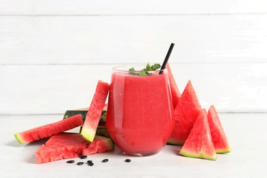 Summer watermelon drink in glass and sliced fresh fruit on table