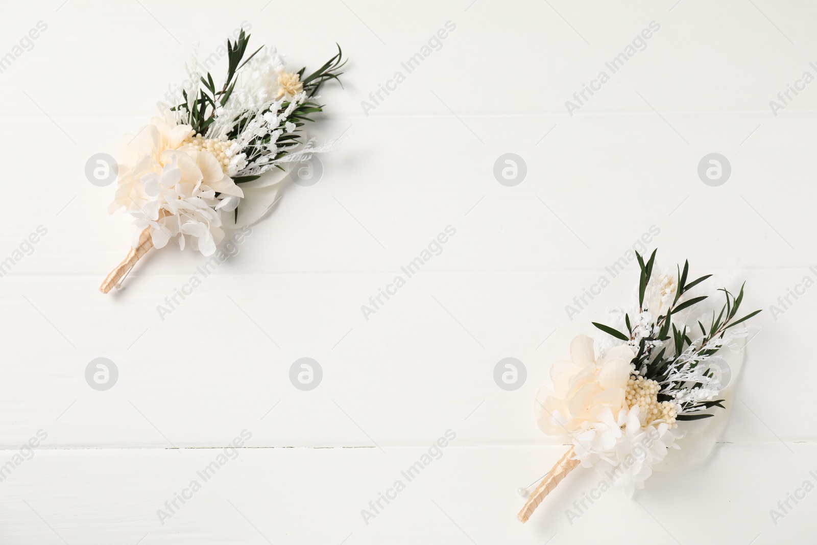 Photo of Beautiful boutonnieres on white background, flat lay. Space for text