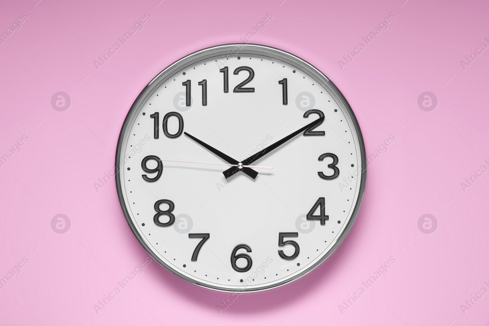 Photo of Stylish round clock on pale pink background, top view. Interior element