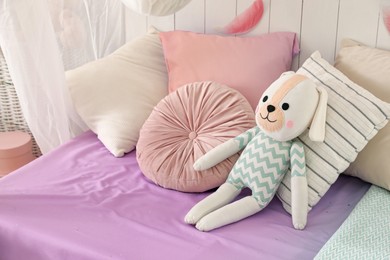 Photo of Comfortable bed with cushions and toy in room. Interior design