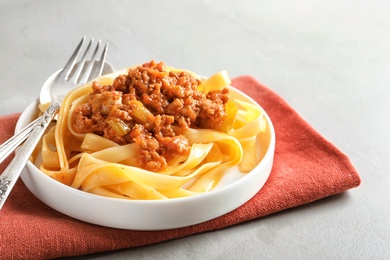 Photo of Plate with delicious pasta bolognese on grey background