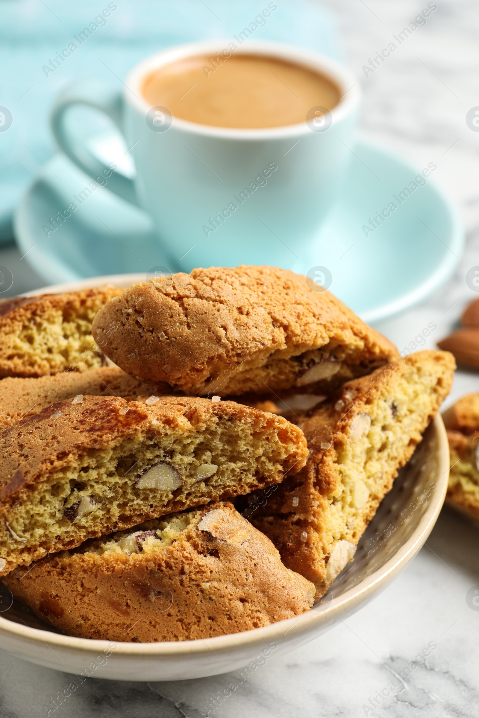 Photo of Tasty cantucci and cup of aromatic coffee on white marble table, closeup. Traditional Italian almond biscuits