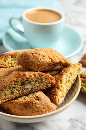 Photo of Tasty cantucci and cup of aromatic coffee on white marble table, closeup. Traditional Italian almond biscuits