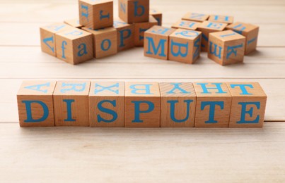Cubes with word Dispute on light wooden table