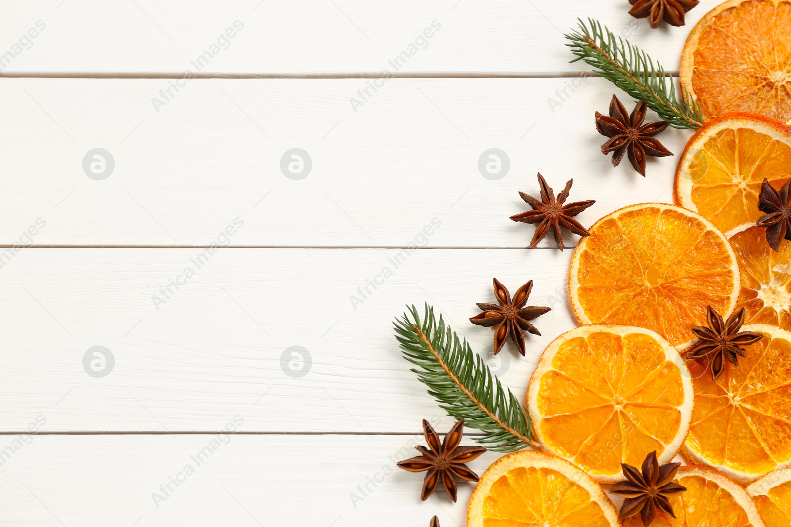 Photo of Flat lay composition with dry orange slices, fir branches and anise stars on white wooden table. Space for text